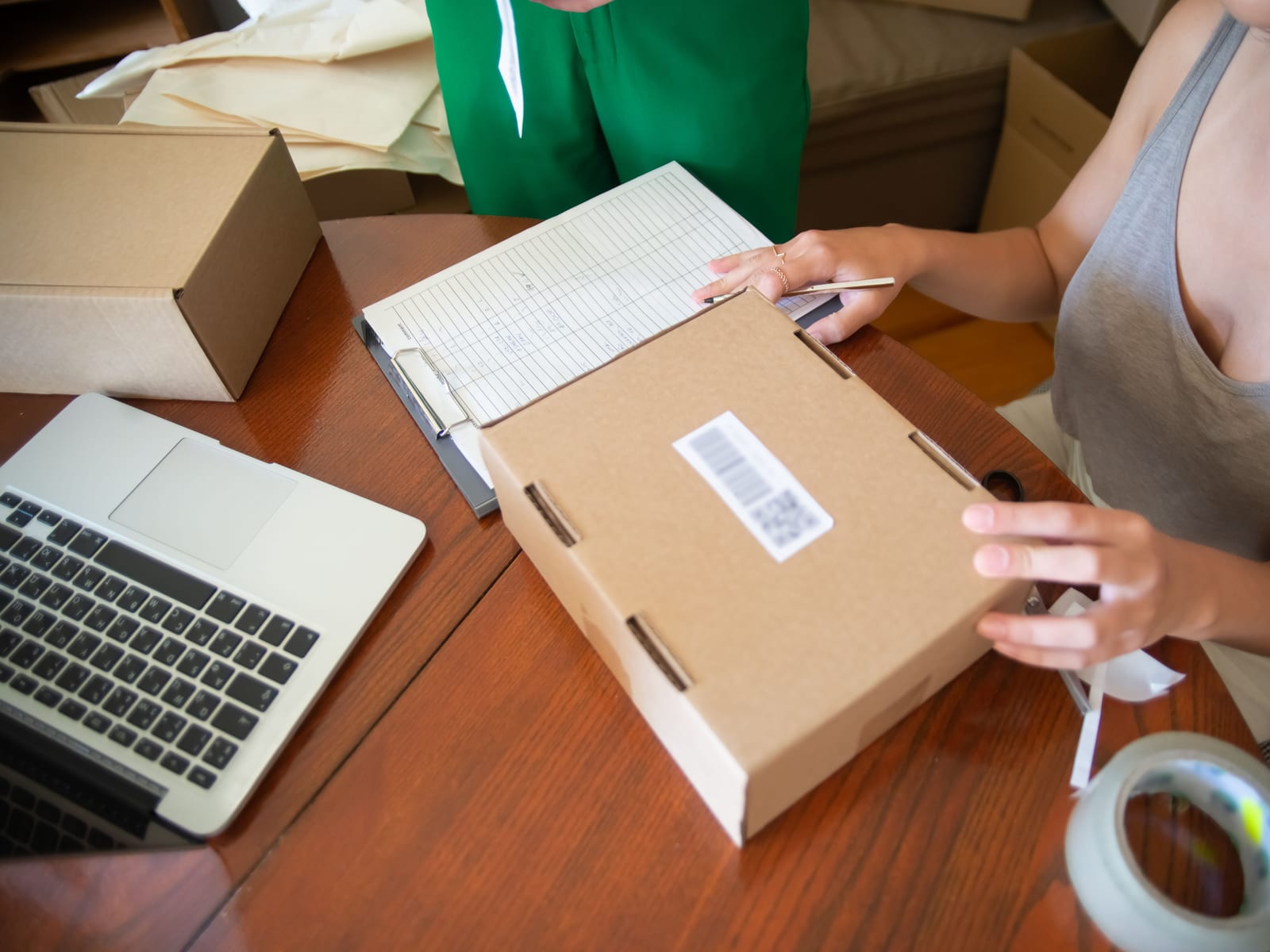 Hands packaging a product order into a branded box